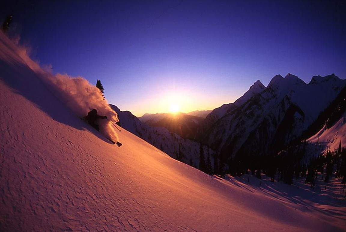 Skifahrer im Tiefschnee bei Sonnenuntergang in den Bergen