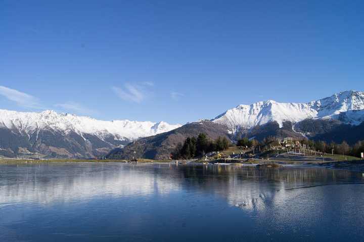 Der gefrorene Bergsee vor der winterlichen Bergkette