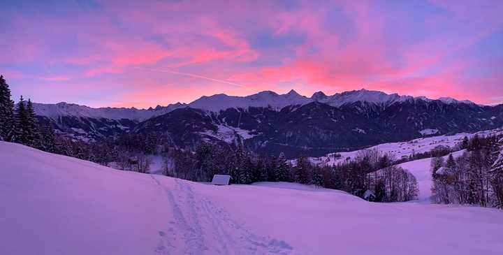 Morgenrot über den Bergen und ein Weg durch den Neuschnee